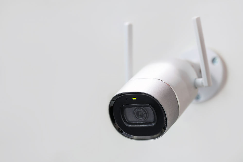 Weiße Überwachungskamera. CCTV an der Wand montiert. WLAN-WLAN-Antennen aktiviert. Großer Bruder beobachtet dein Konzept